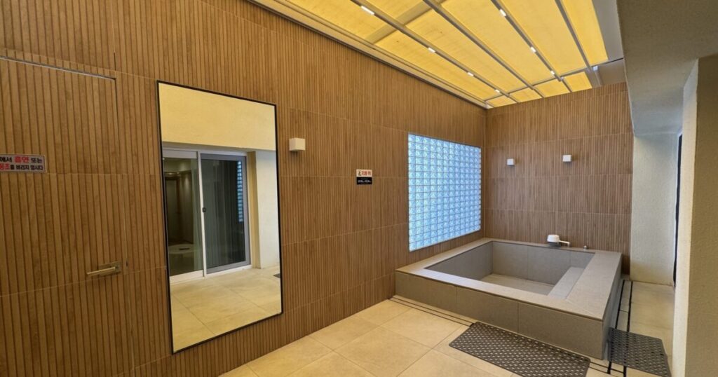 Private open-air bath in the Terrace Spa room at Deokgu Hot Springs Hotel, Uljin, featuring a large bathtub and an automatically retractable ceiling