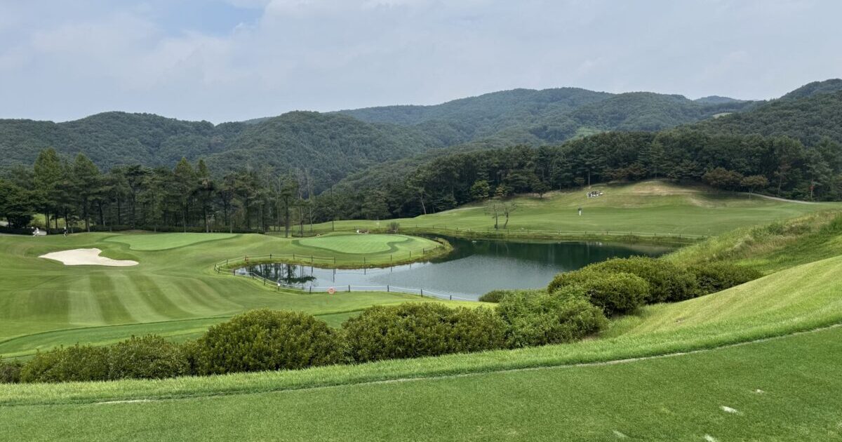 A male golfer performing a powerful driver tee shot at Asiana CC East Course, a luxury golf course near Seoul, South Korea.